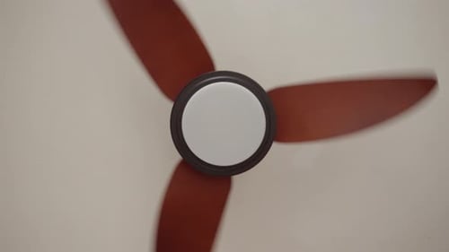 Brown Ceiling Fan Spinning Against White Ceiling