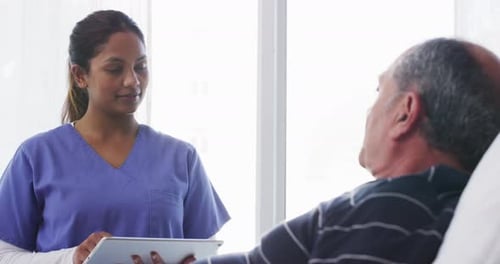 Doctor talking to patient in hospital. Nurse consulting with senior man in a bed