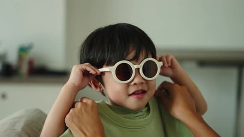 Cute Child Plays with Fashionable Sunglasses Indoors
