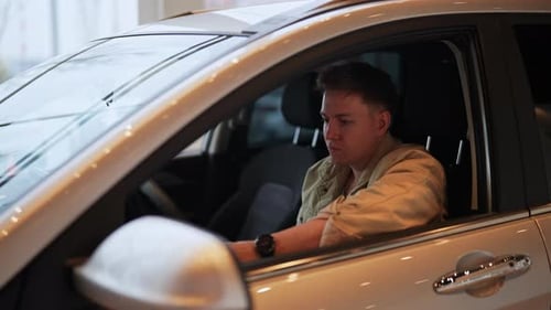 Satisfied Customer Male Sitting in Driver Seat in New Automobile Inside Modern Showroom Happy Young