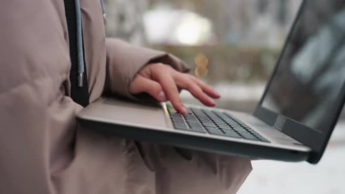 Hand Typing on Laptop with Blurred Screen and Soft Winter Background
