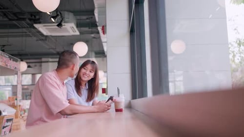 Two couples sat and talked while resting at a cafe. They looked at their smartphones.