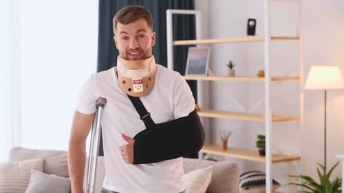 Man With Neck Brace and Arm Sling Gives Thumbs-Up
