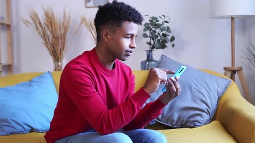 Young Adult Using Smartphone on Couch at Home