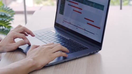Hands Typing on Laptop with Charts and Graphs
