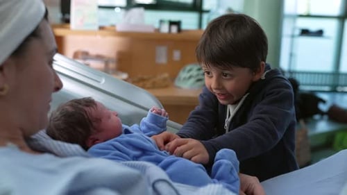 Bonding family moment of sibling interacting with his newborn baby brother at hospital after