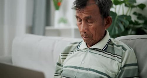 Senior Man Relaxing on Sofa with Laptop Indoors
