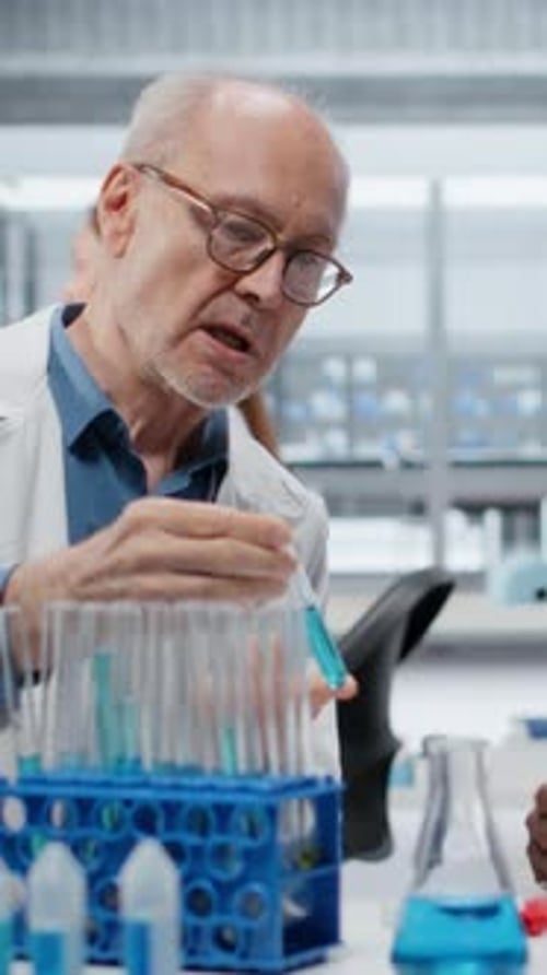 Vidéo verticale Des biologistes moléculaires travaillant en équipe dans un laboratoire évaluent une solution de composé bleu