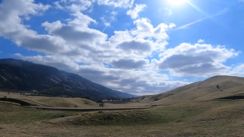 Rolling Fields with Mountain Backdrop on Sunny Day