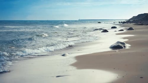 Gentle low waves roll slowly on the clean sandy beach
