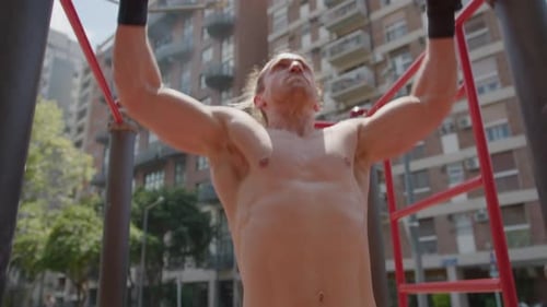 Muscular Man with Shirtless Torso Doing Bar Pull Ups Outdoors