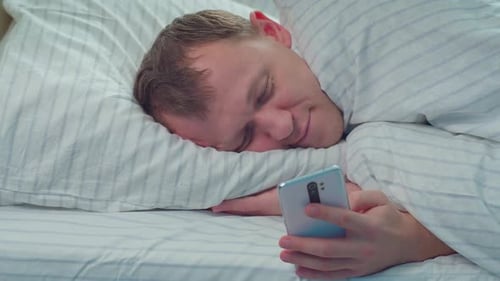 Adult Sleeping in Bed While Holding Phone