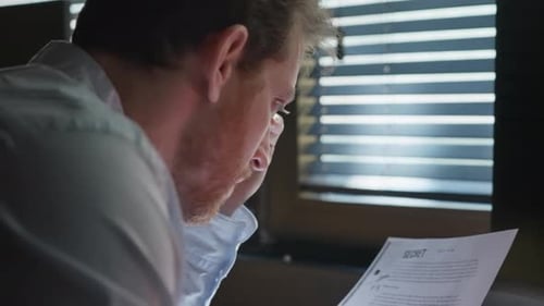 Businessman, agent, or investigator reviewing a secret file, marking key details with a red marker.