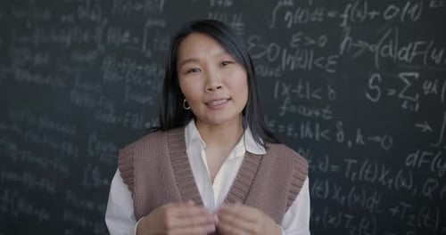 Confident Woman Explains Math in Front of Chalkboard
