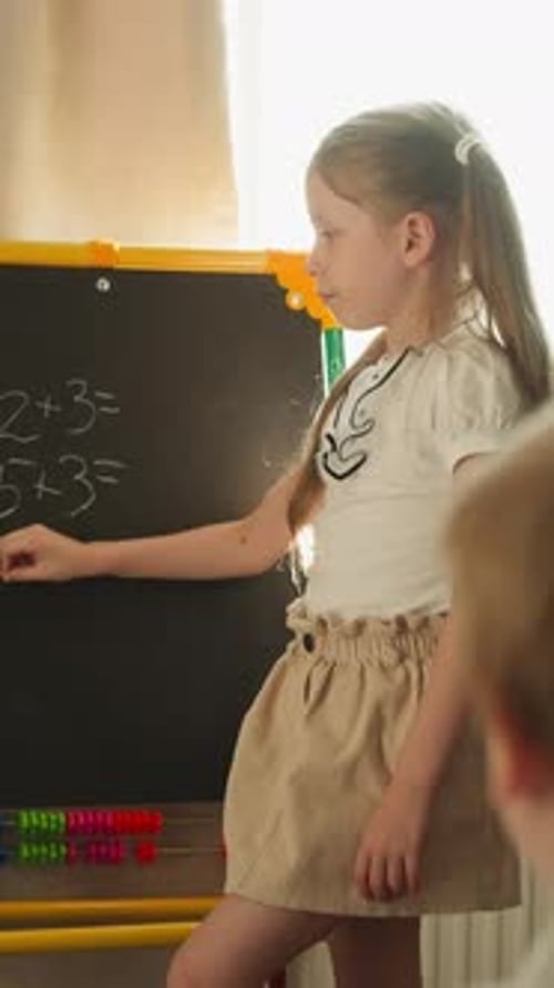 Girl Writes on Blackboard with Tiny Piece of Chalk