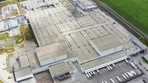 Rooftop of a big factory on field. Flight over industrial complex.