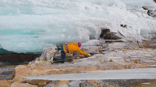 Mountain Climber Ascends Rock Face Near Glacial Ice