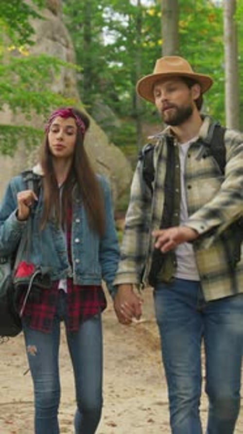 A Couple Hikes Through a Lush Forest Holding Hands and Sharing Joyful Moments Together