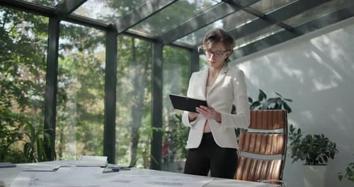 A Young Woman Architect Holding and Working with Tablet Pc Pad at Her Work Office with Big Sunlight