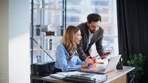 Chef hilft einer Mitarbeiterin bei der Arbeit an einem Startup, das einen Laptop im modernen Büro sucht