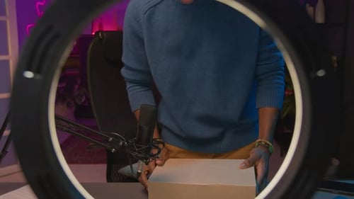 Man Unboxes White Headphones in Front of Ring Light