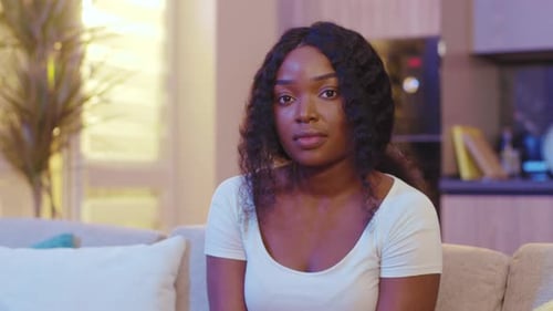 Woman Sits Thoughtfully on Couch in Living Room