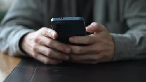Closeup hands using smartphone device. Hand holding cellphone browsing internet touching screen.