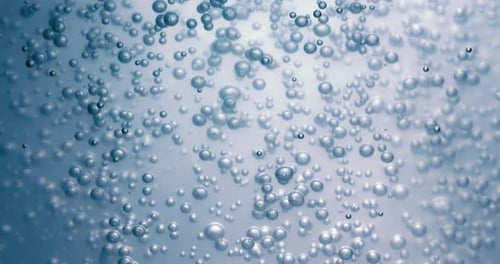 Many water bubbles in blue water close up, abstract water wave with bubbles in slow motion.