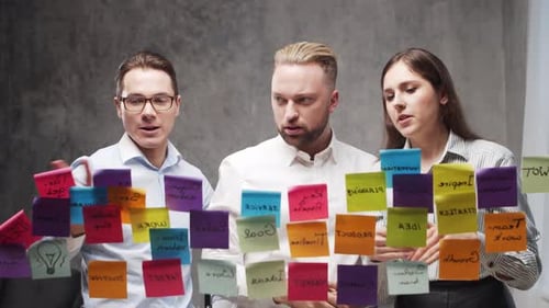 Team of Business People is Doing Brainstorm at a Meeting Using Stickers on the Glass Office Workers