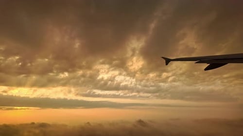 View from airplane window. Dawn flight with scattered clouds obscuring the sun