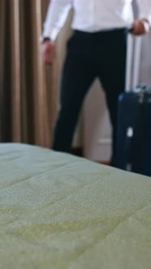 Unrecognizible businessman has just entered a hotel room and ready to unpack suitcase.