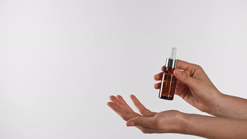 Woman's Hand Presents Amber Dropper Bottle Product
