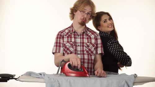 Young Adult Couple Ironing Clothes At Home