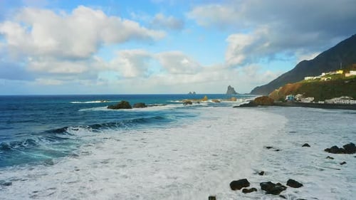 Rocky volcanic shoreline on north of Tenerife with foaming ocean waves. Aerial mountain nature lands