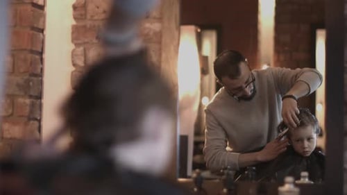 Child Gets Haircut at Barbershop by Male Barber
