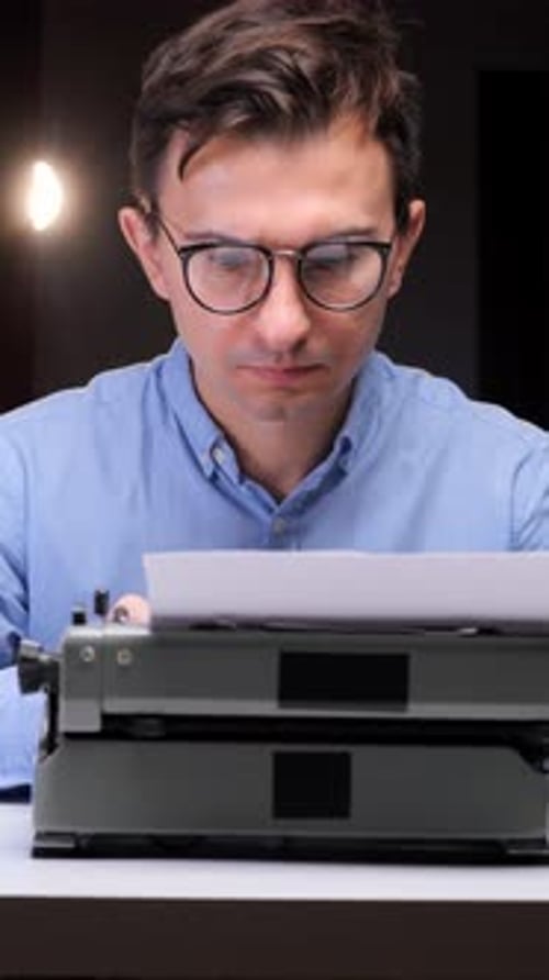 Man Types on Vintage Typewriter in Dark Room