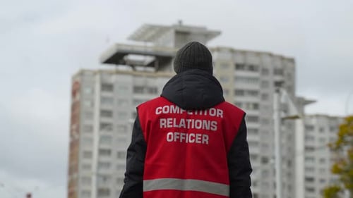 Homme en gilet rouge avec inscription sur le dos Officier des relations avec les concurrents