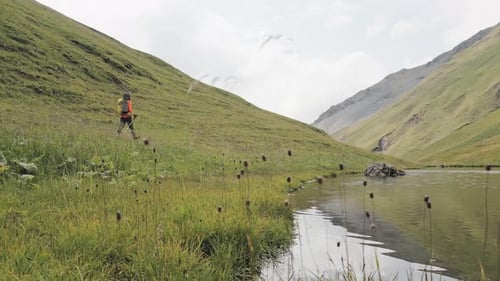 Hiker trekking through idyllic mountain landscape alongside lake