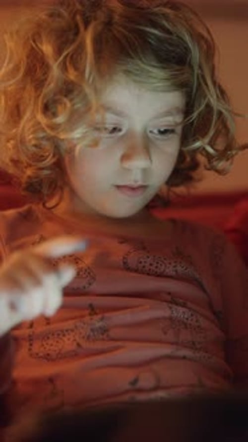 Small Girl Plays or Watches a Tablet Computer in Vertical