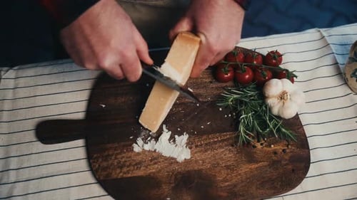 Man Slicing Parmesan Cheese on Wooden Board