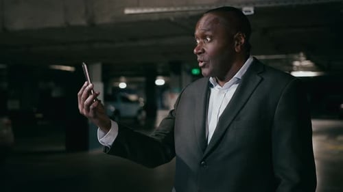 Angry Annoyed African American Man Talk on Video Call Using Phone in Underground Parking Lot Poor