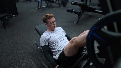 Fitness man exercising in modern gym and doing leg press, weightlifting leg workout slow motion