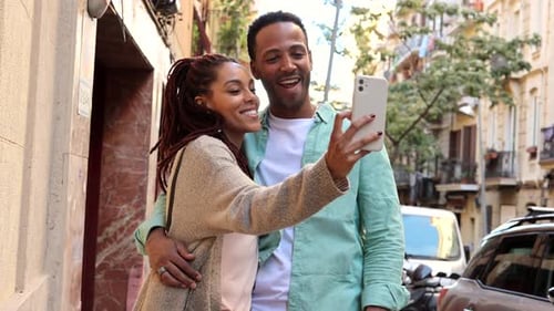 romantic relationship. Young diverse couple walking on city street embracing woman browsing internet