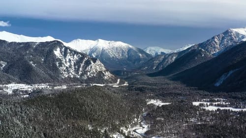 Air flight through mountain clouds over beautiful snow-capped peaks of mountains and glaciers.