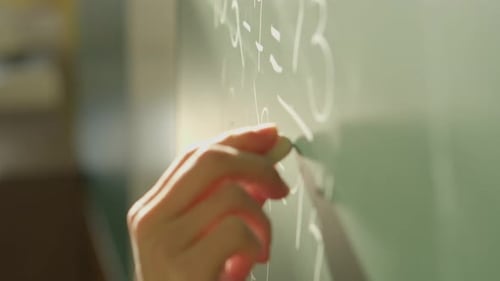 Hand Writes Math Equations on Chalkboard Close Up