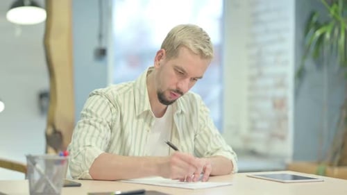 Young Man Writing Letter in Office