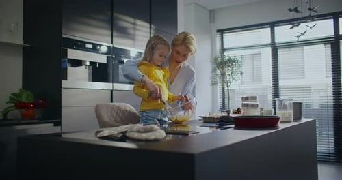 Charming Caucasian Woman Talking with Her Daughter Showing Girl Correct Way of Mixing Ingredients