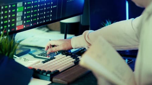 Trader Analyzes Data on Computer Screen at Desk