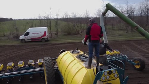Blue tractor with yellow seeder working on the field in Ukraine OA