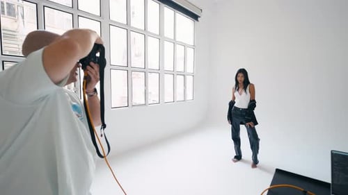 Photographer Taking Pictures of Model Posing in White Studio